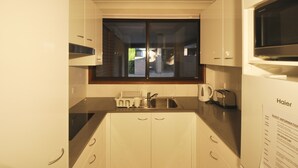 A modern kitchen with white cabinets, a stainless steel sink, a toaster, and a kettle. - Katoomba Townhouses (Katoomba)