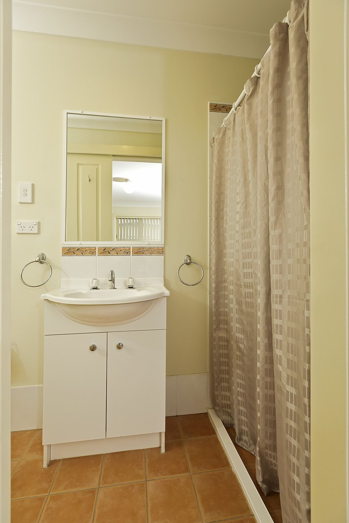 Un bagno con un lavandino bianco, uno specchio e due appendi-asciugamani.