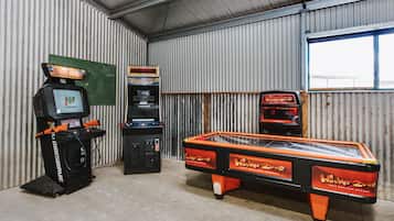 Une pièce équipée d’une table de billard, d’un flipper et d’une console de jeux vidéo.