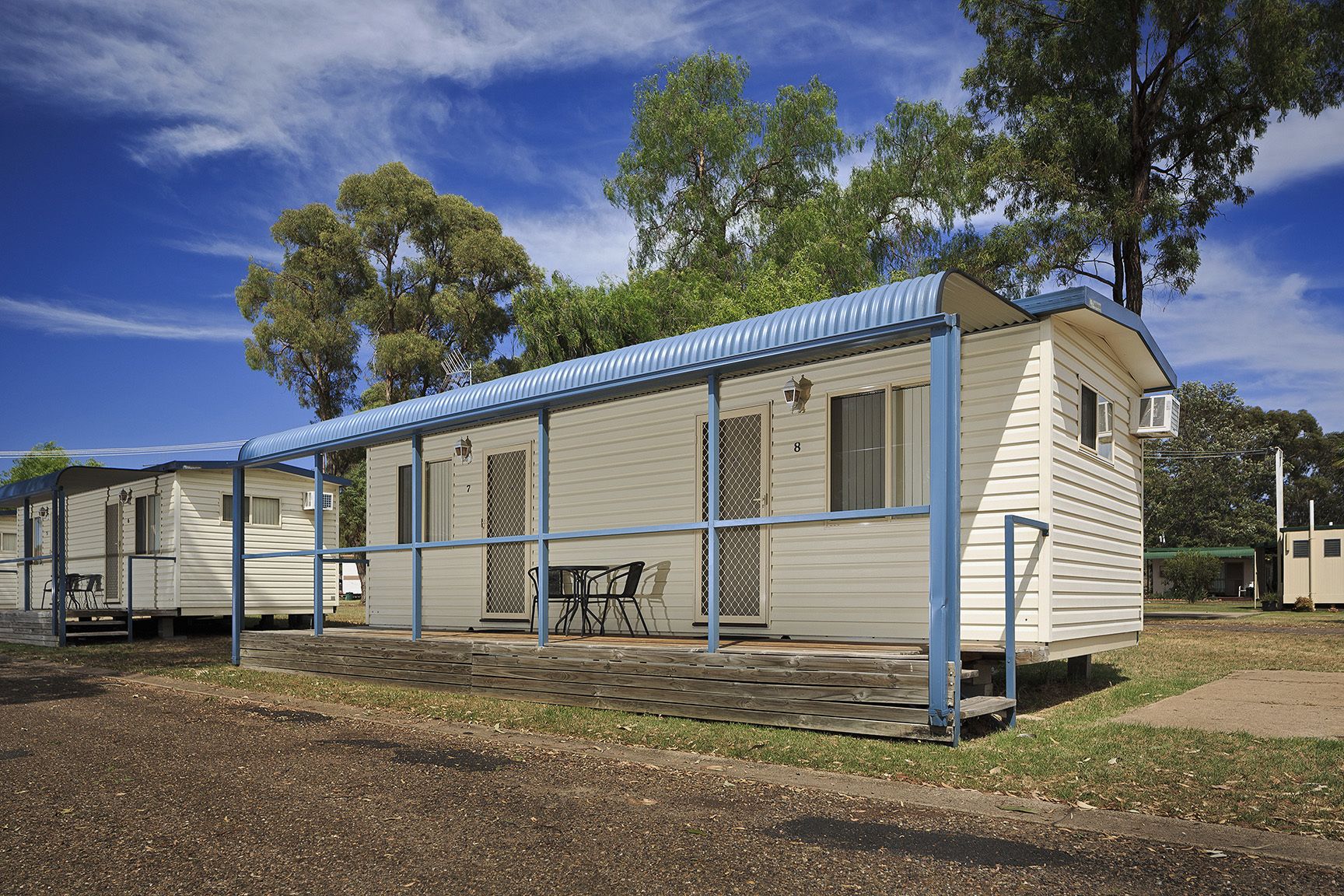 A row of mobile homes with a covered patio area, each with a number on the door.