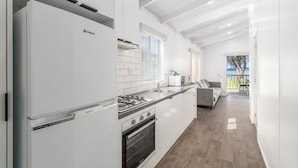 A modern kitchen with white cabinetry, a gas stove, and a built-in oven.