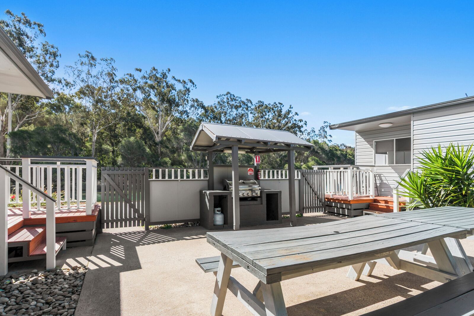 A backyard with a barbecue area, a picnic table, and a fenced deck.