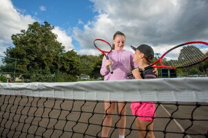 Dos personas en una cancha de tenis sosteniendo raquetas.