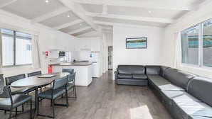 A modern kitchen with white cabinets, a dining area with a table and chairs, and a living area with a sofa.
