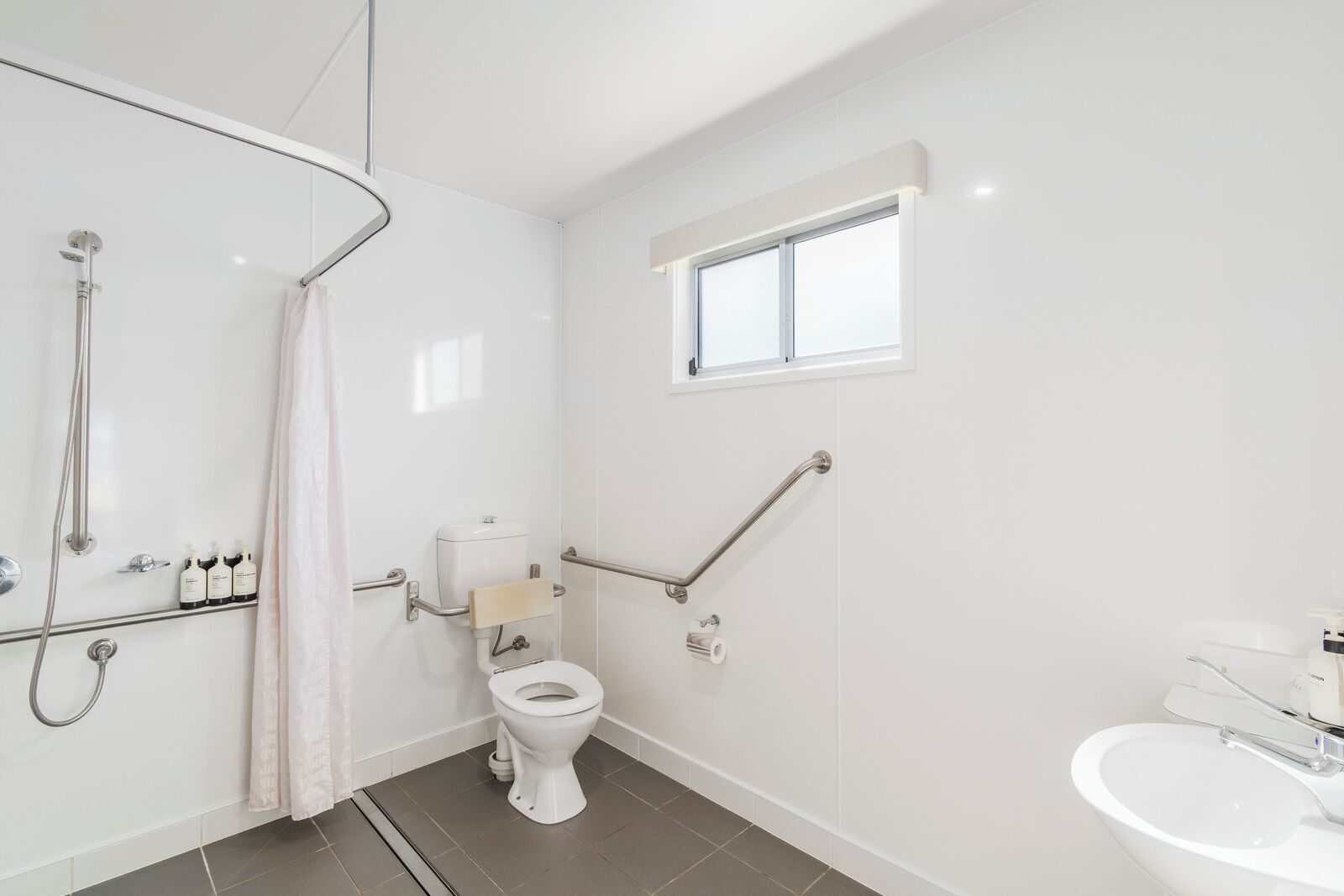 A modern bathroom with a toilet, shower, and sink.