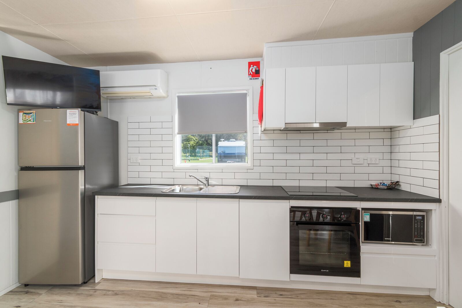 A modern kitchen with white cabinets, a stainless steel refrigerator, a sink, a stove, and a dishwasher.
