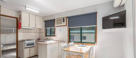 Cocina compacta con estufa, lavamanos y comedor.