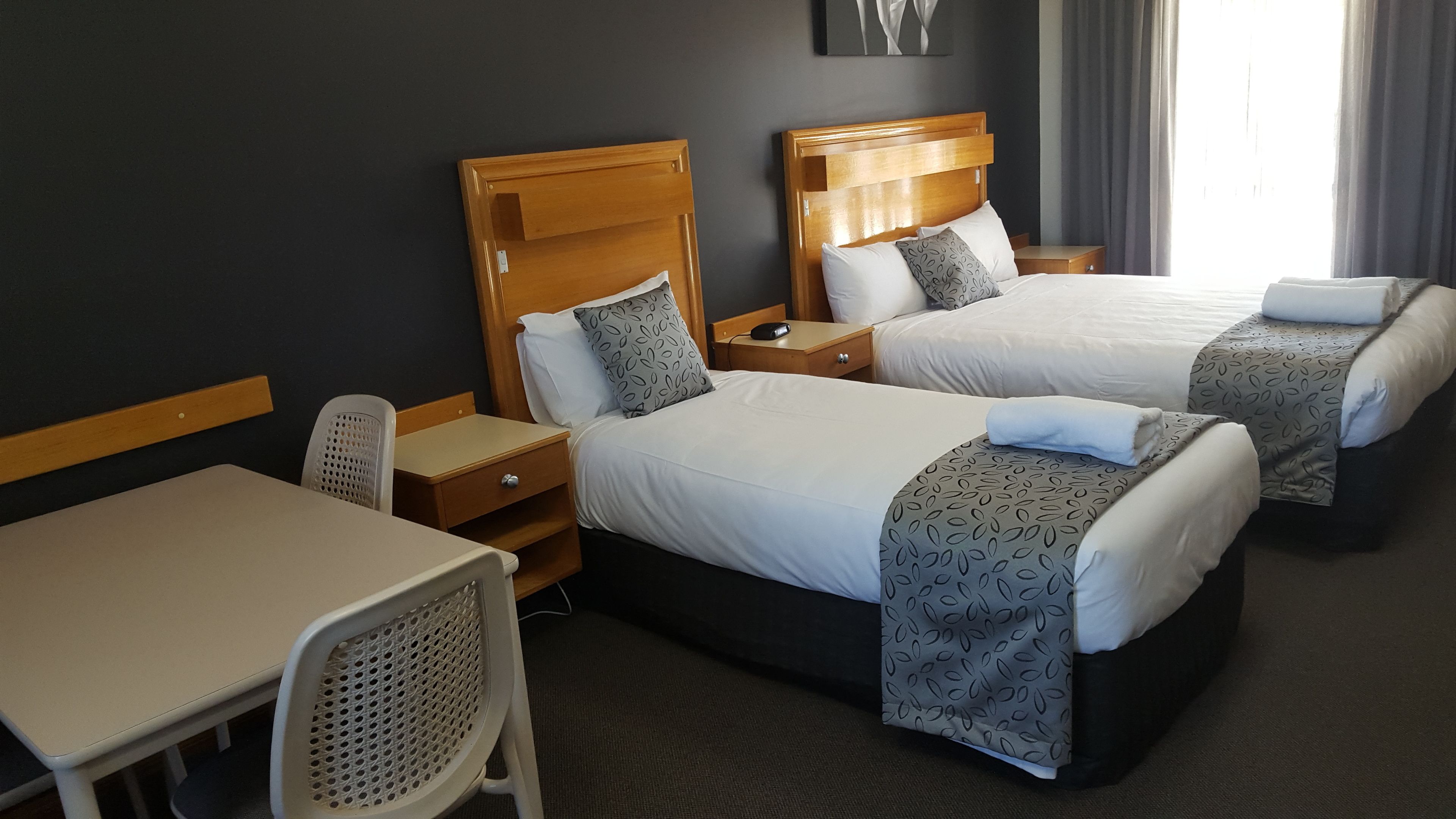 Una habitación de hotel con dos camas individuales, un escritorio pequeño y una silla.