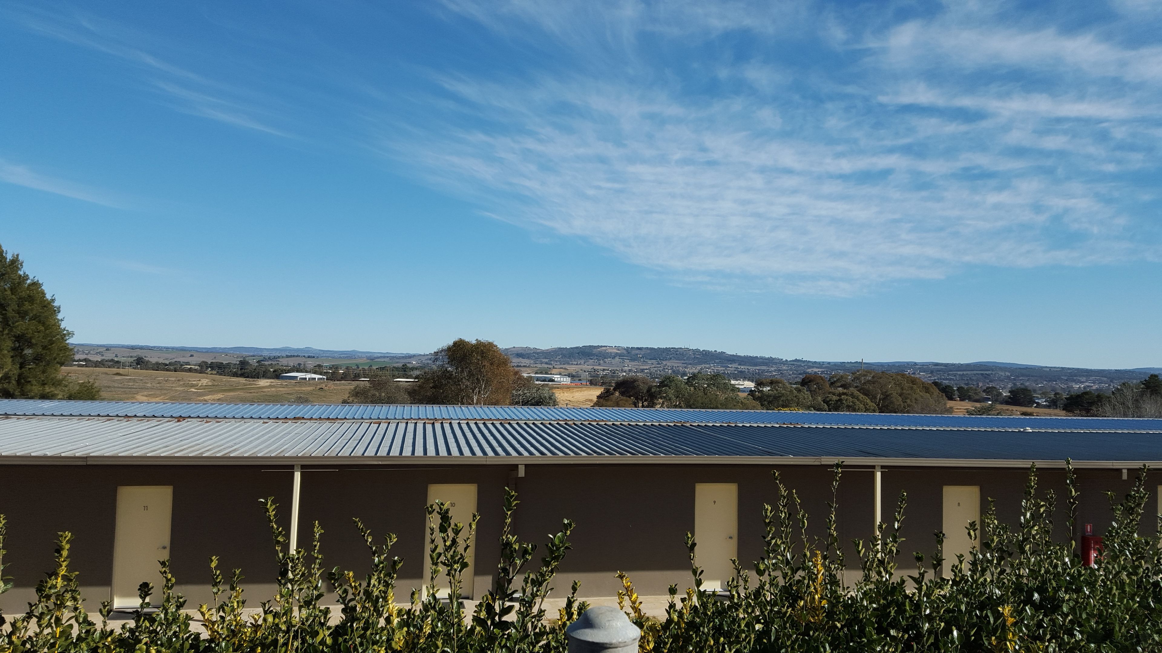 A hotel with a flat roof, a view of the countryside, and a clear sky.
