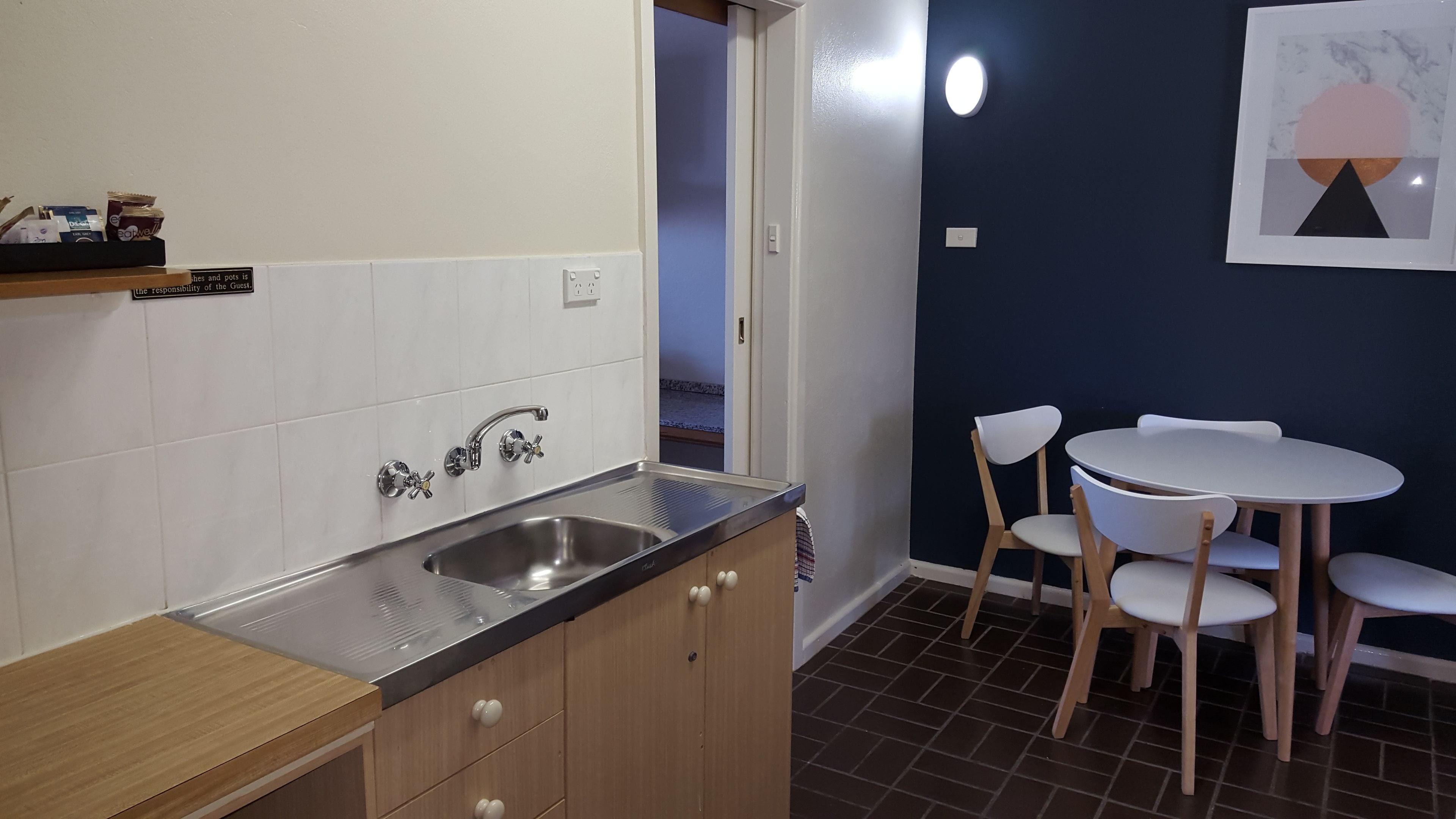 Una cocina compacta con lavamanos, armarios y una zona de comedor con sillas y una mesa.
