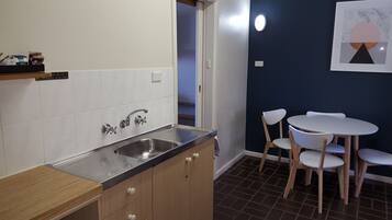Una cocina compacta con lavamanos, armarios y una zona de comedor con sillas y una mesa.