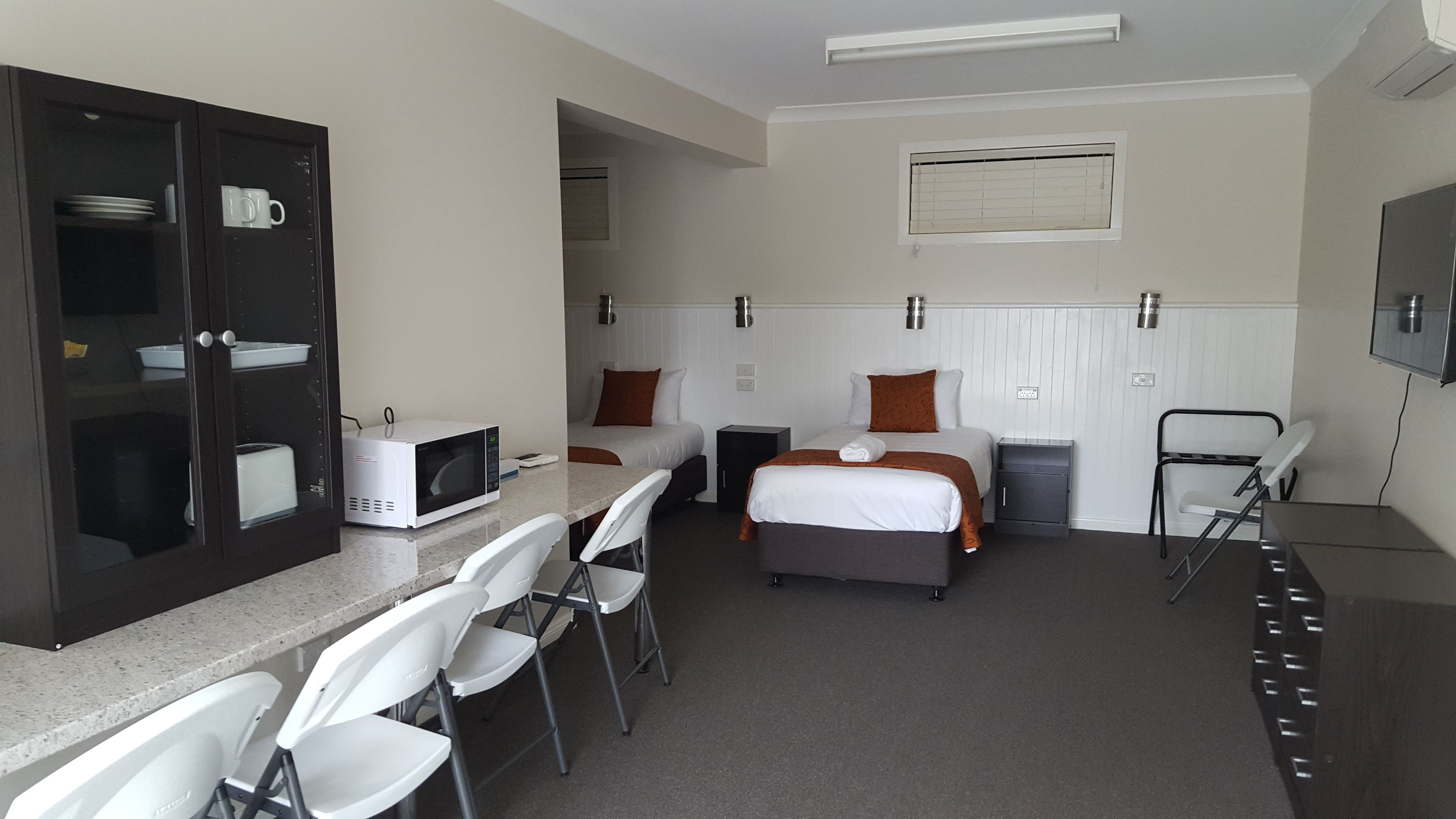 A hotel room with two beds, a microwave, a small table, and a seating area with chairs.