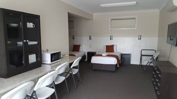 A hotel room with two beds, a microwave, a small table, and a seating area with chairs.