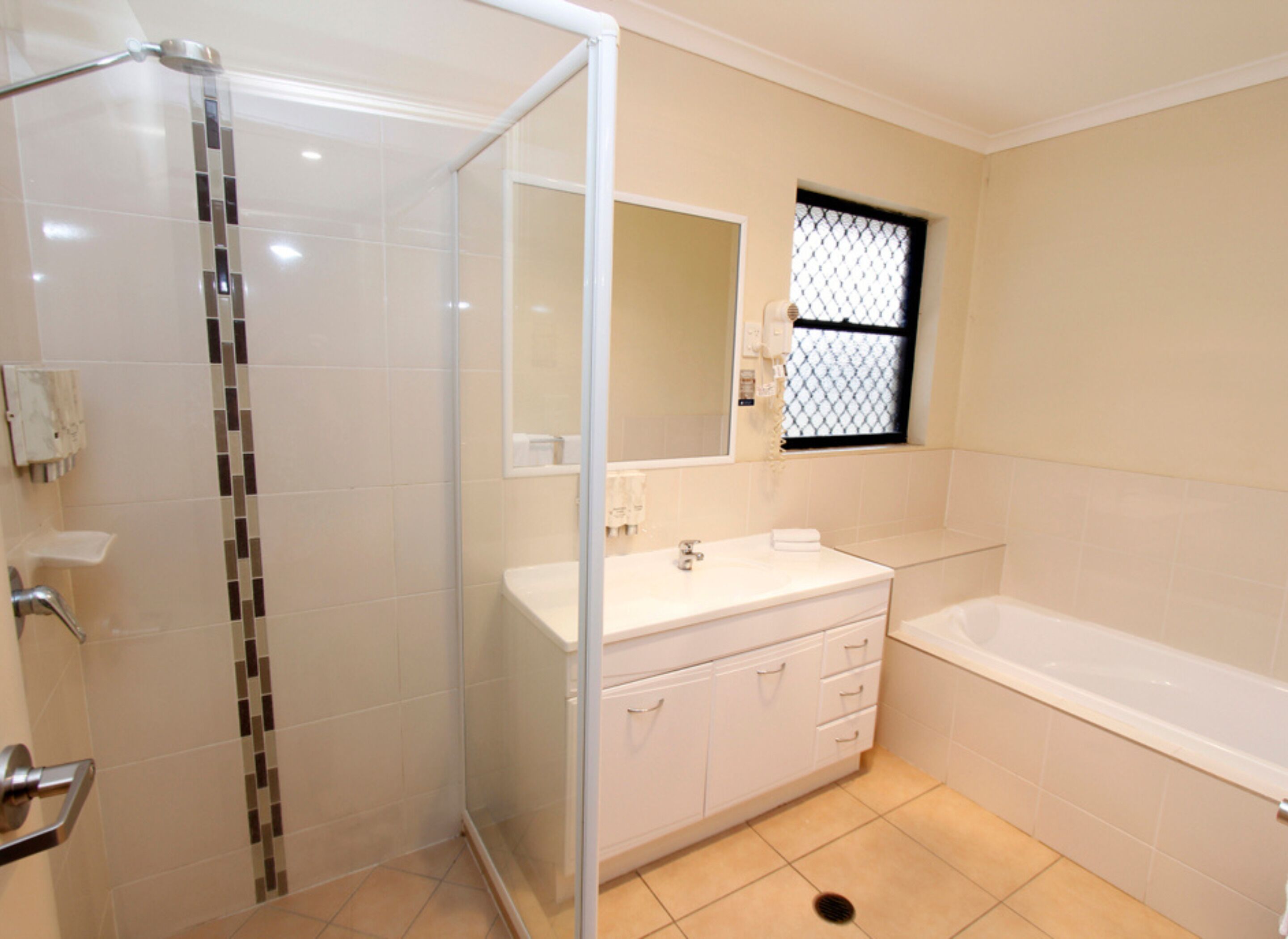 A bathroom with a glass shower enclosure, a sink with a mirror, and a bathtub.