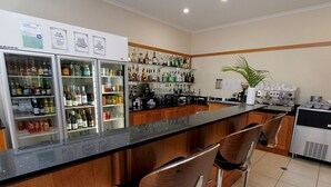 Eine Bar mit einer Theke, Hockstühlen und einem mit Getränken gefüllten Kühlschrank.