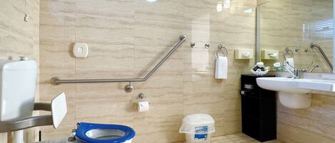 A bathroom with a toilet, handrails, a sink, and a mirror.