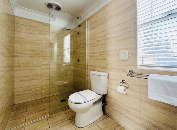 Un baño con ducha de vidrio, inodoro y barra para toallas.