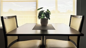 A dining table with two chairs, a potted plant, and a window with blinds. - Gunnedah Lodge Motel (Gunnedah)