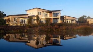 A modern two-story house with a large balcony, situated by a calm lake. - Broadbeach Inverloch Resort (Inverloch)