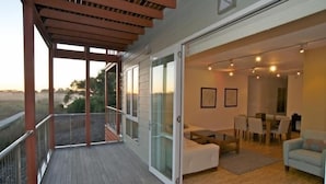 A modern living room with a glass door leading to a balcony, a dining area with a table and chairs, and a light blue sofa. - Broadbeach Inverloch Resort (Inverloch)