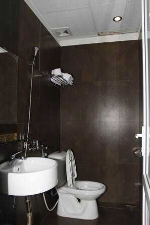 A modern bathroom with a white sink, toilet, and shower. - Golden Beach Hotel (Da Nang)
