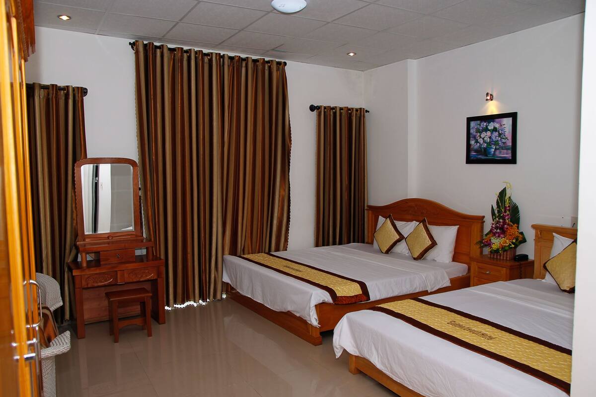 A hotel room with two beds, a wooden dresser, a mirror, and a painting on the wall.