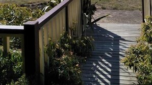 A wooden deck leading to a grassy field with mountains in the background. - Halls Gap Valley Lodges (Halls Gap)