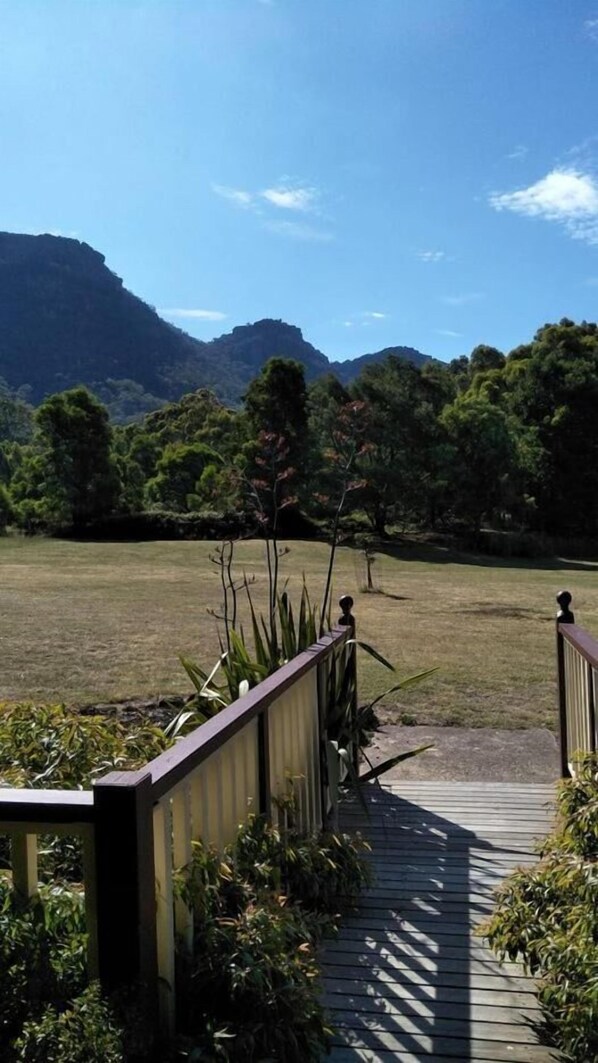 A wooden deck leading to a grassy field with mountains in the background. - Halls Gap Valley Lodges (Halls Gap)