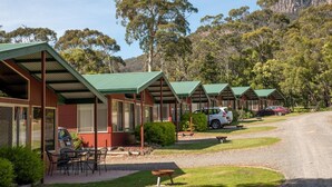 A row of cabins with green roofs, a gravel path, and a car parked in front. - Halls Gap Valley Lodges (Halls Gap)