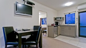 Una habitación de hotel compacta con comedor, kitchenette y un ventanal grande.