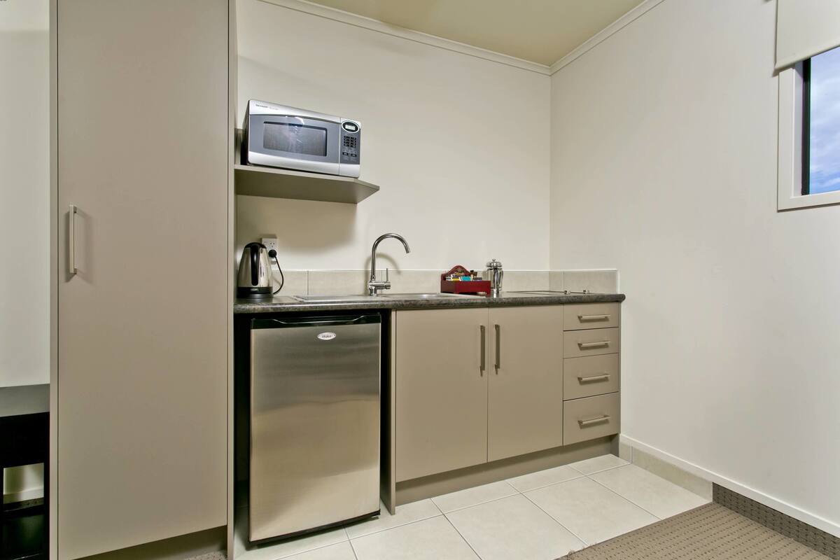 A compact kitchen with a built-in microwave, a coffee maker, and a dishwasher.