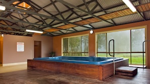 A spa room with a wooden hot tub, large windows, and a high ceiling with metal beams. - Mansfield Country Resort (Mansfield)