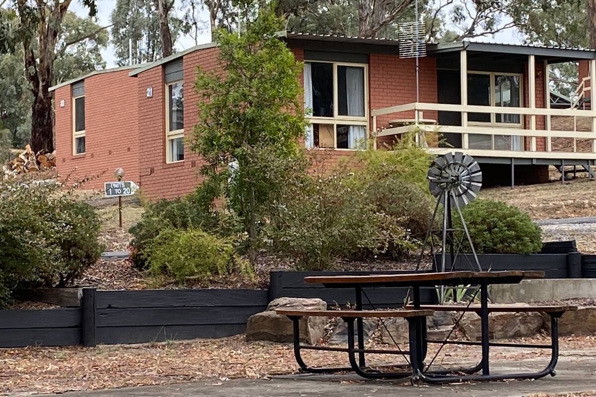 A rustic building with a windmill, a picnic table, and a sign indicating unit availability.