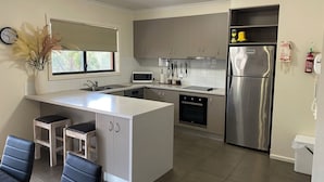 A modern kitchen with a central island, stainless steel appliances, and a dining area with two chairs. - Mansfield Country Resort (Mansfield)