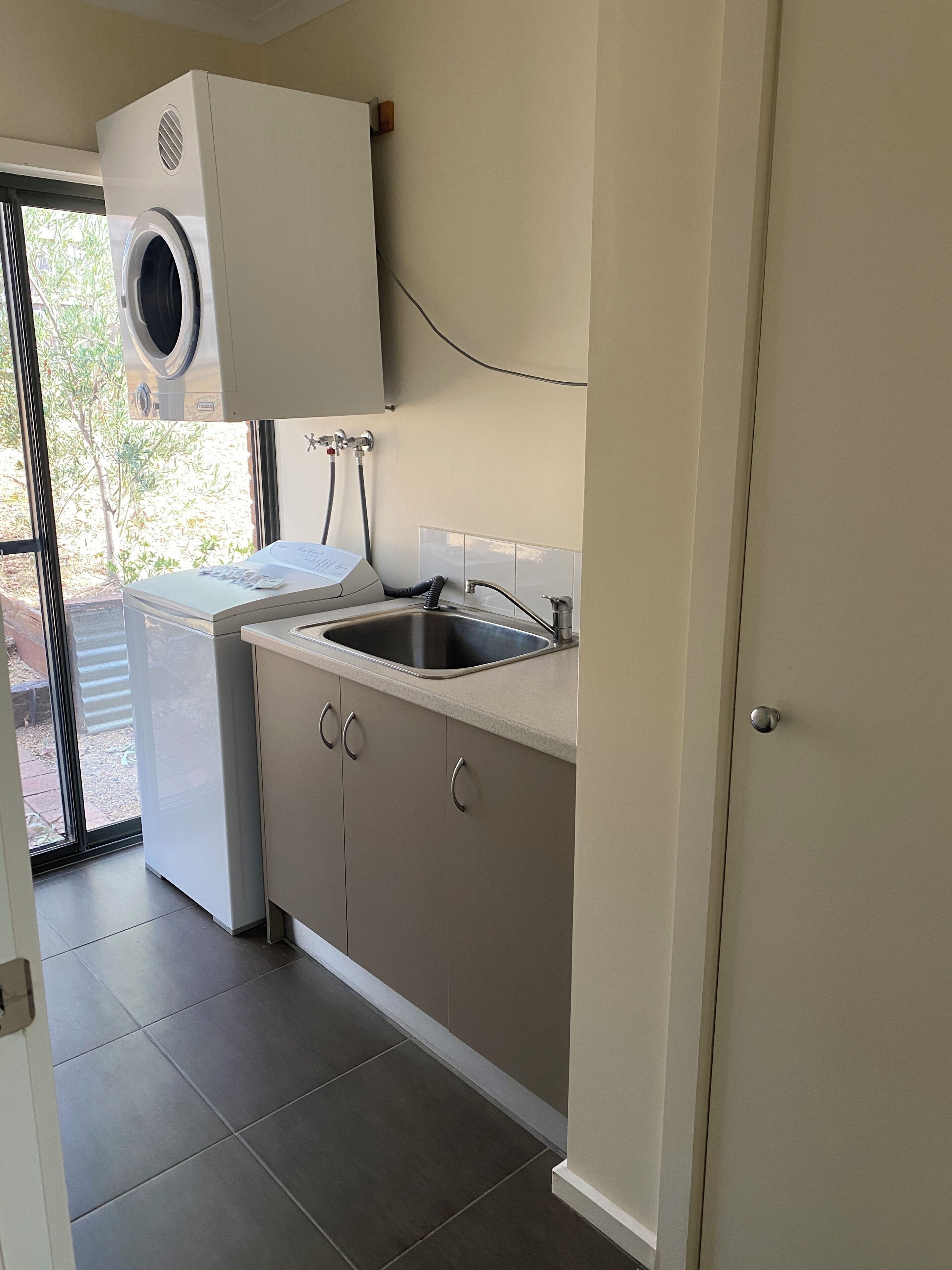 A compact kitchen with a built-in washer and dryer, a sink, and cabinets.