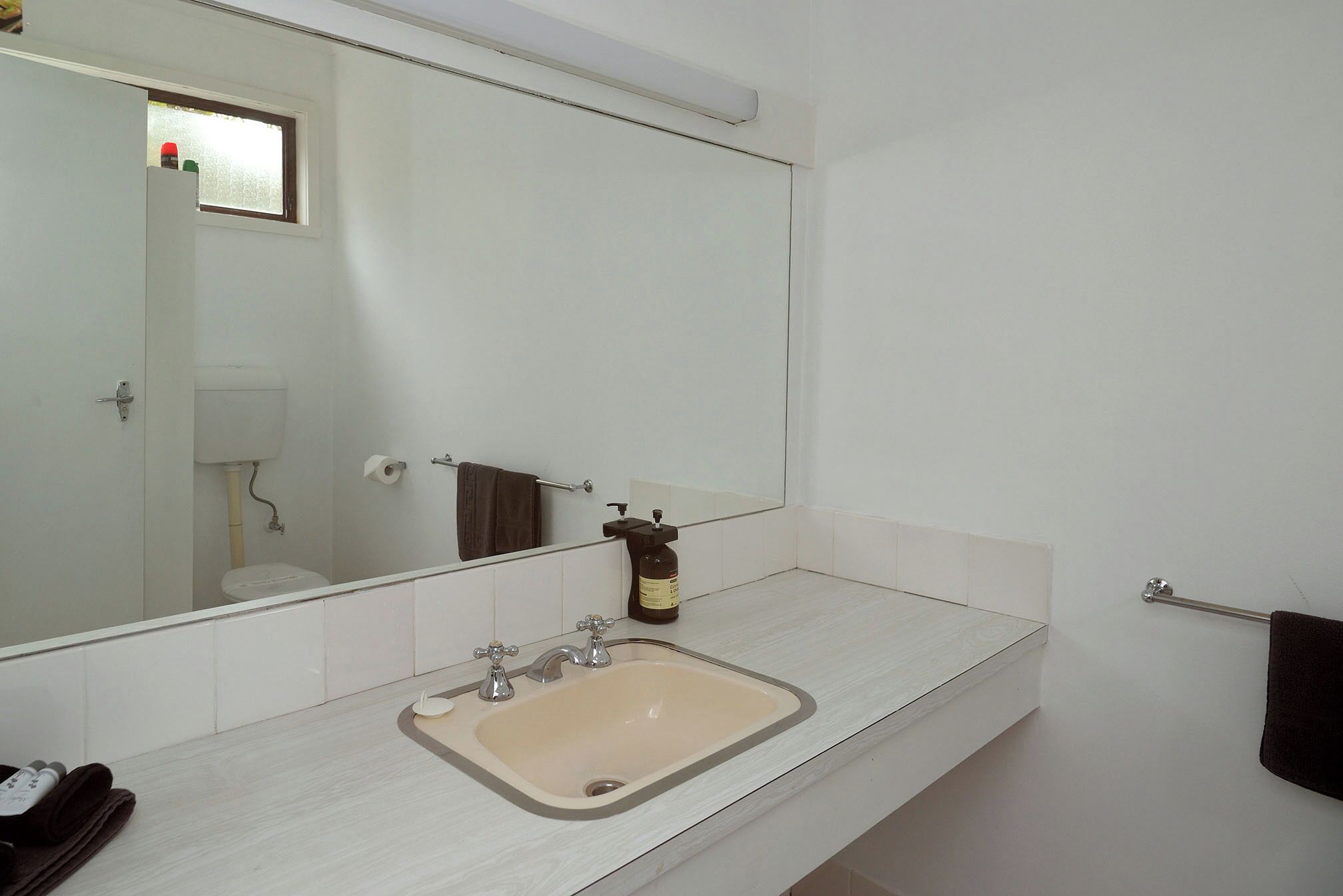 Une salle de bain équipée d’un lavabo, d’un miroir, d’un porte-serviettes et d’un savon.