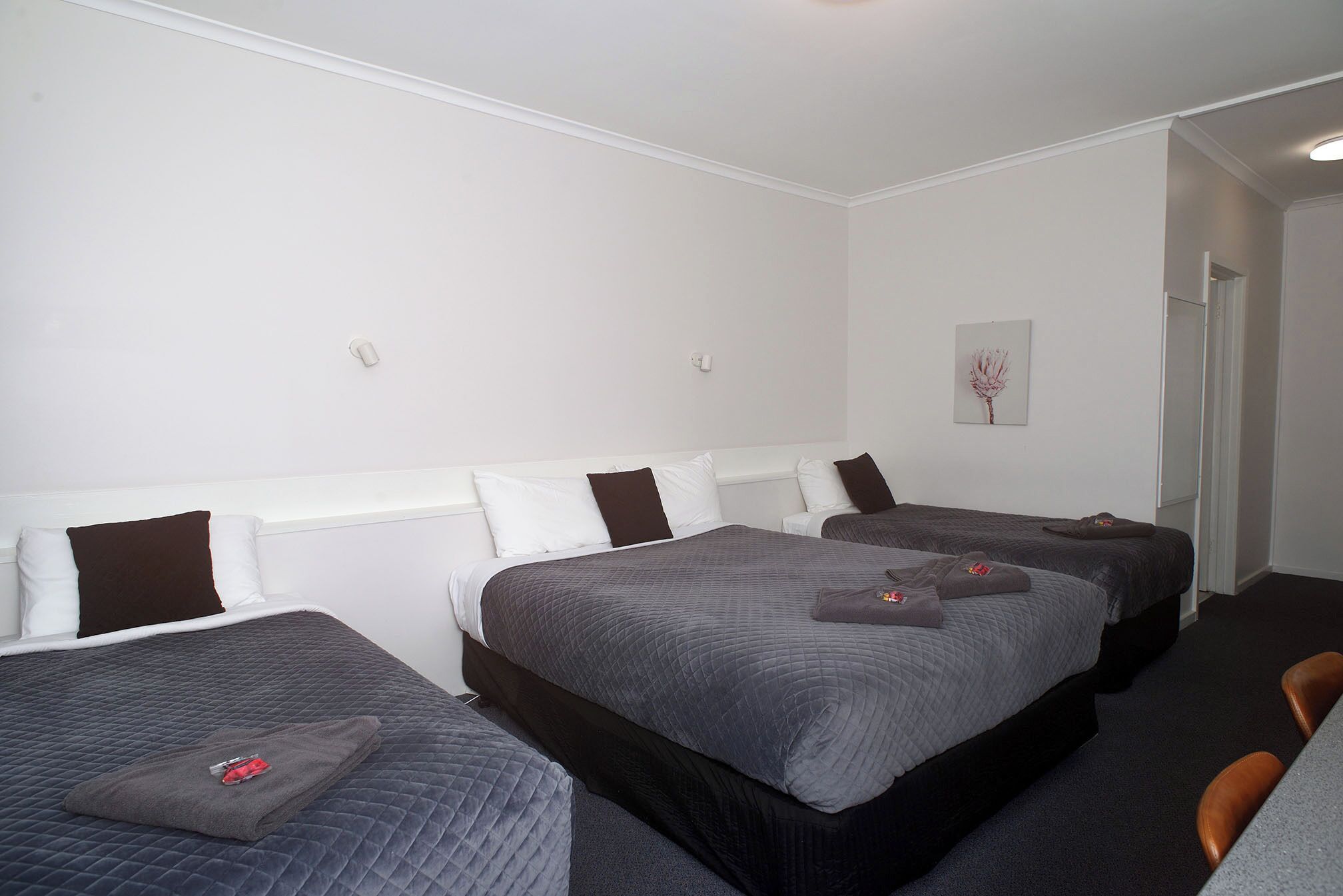 A hotel room with three beds, a small table, and a chair.
