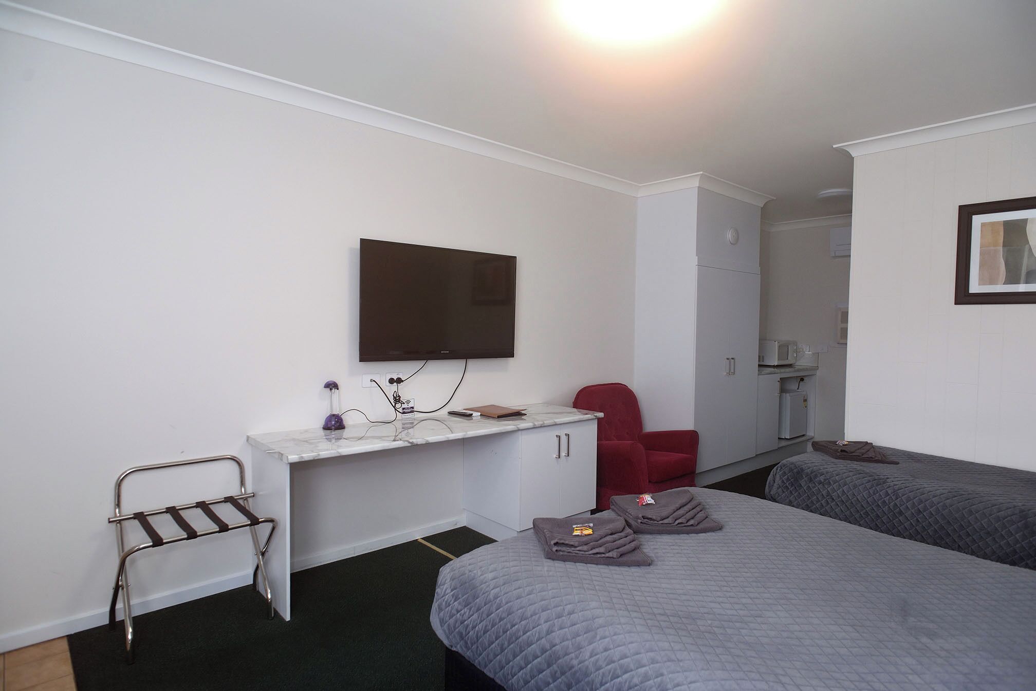 A hotel room with a bed, a desk, a chair, a TV, and a wardrobe.