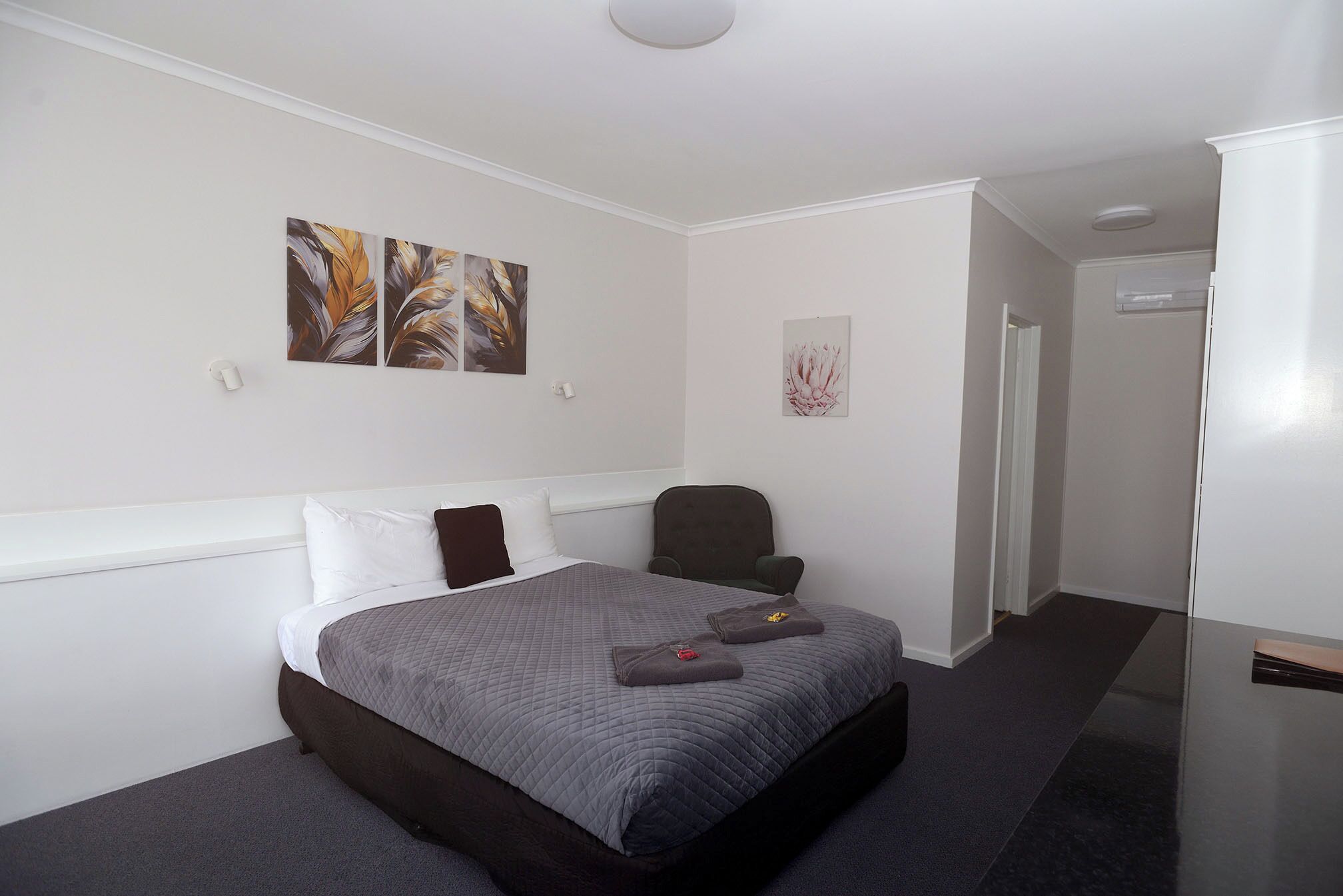 Ein Hotelzimmer mit Bett, Sessel und Bildern an den Wänden.