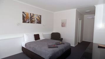 Ein Hotelzimmer mit Bett, Sessel und Bildern an den Wänden.