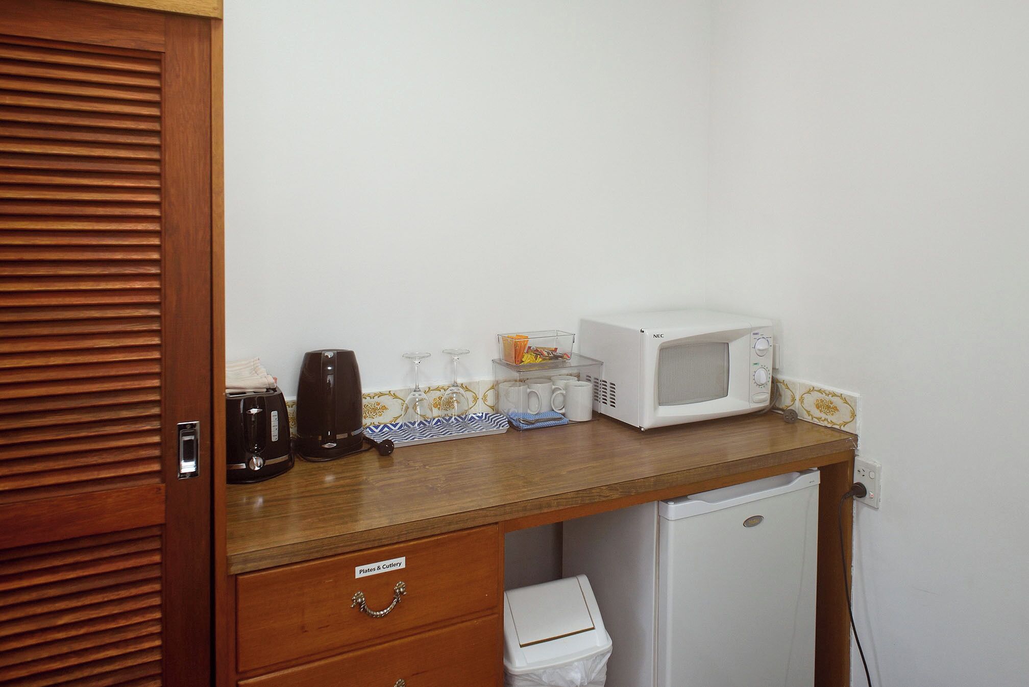 Cocina compacta con microondas, tostadora y cafetera sobre una encimera de madera.