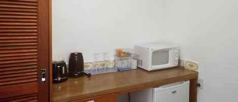 Cocina compacta con microondas, tostadora y cafetera sobre una encimera de madera.