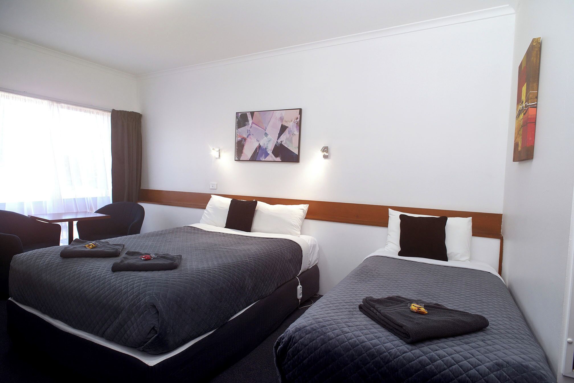 Habitación de hotel con dos camas, un escritorio y una silla.