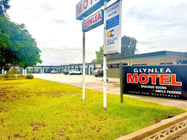 A motel with a signboard advertising spacious rooms, ample parking, and new management.