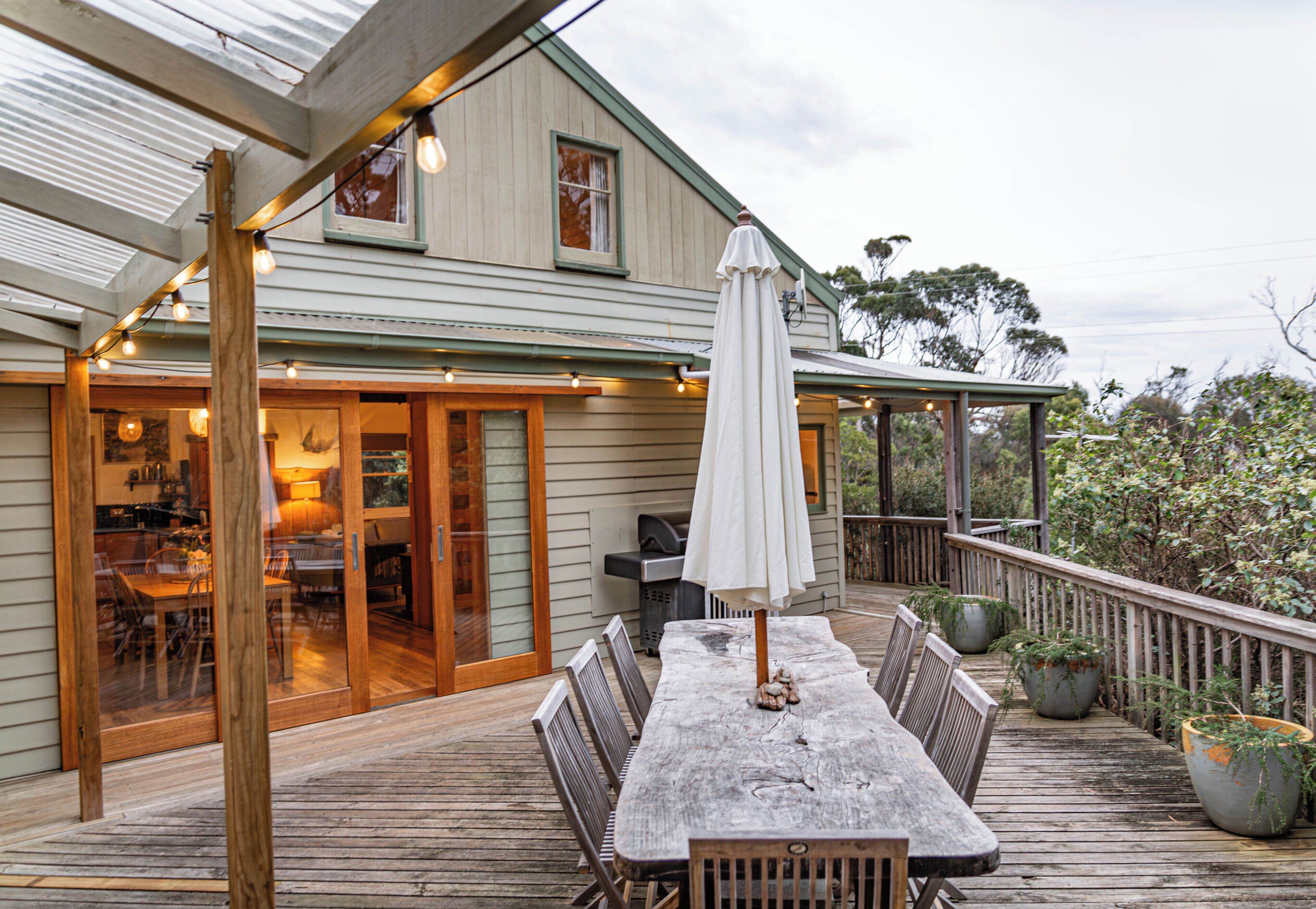 A wooden deck with a table and chairs, a barbecue grill, and a covered patio area.