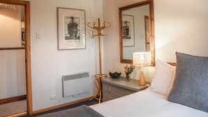 Ein Hotelzimmer mit Bett, Nachttisch, Lampe und einem gerahmten Bild an der Wand.