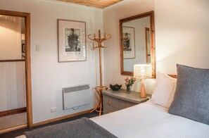 Habitación de hotel con cama, mesita de noche, lámpara y un cuadro en la pared.