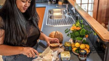 A person preparing food at a kitchen counter with bread, a jar of honey, and a bowl of lemons.
