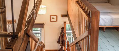 A wooden staircase leading to a bedroom with a bed and a window.
