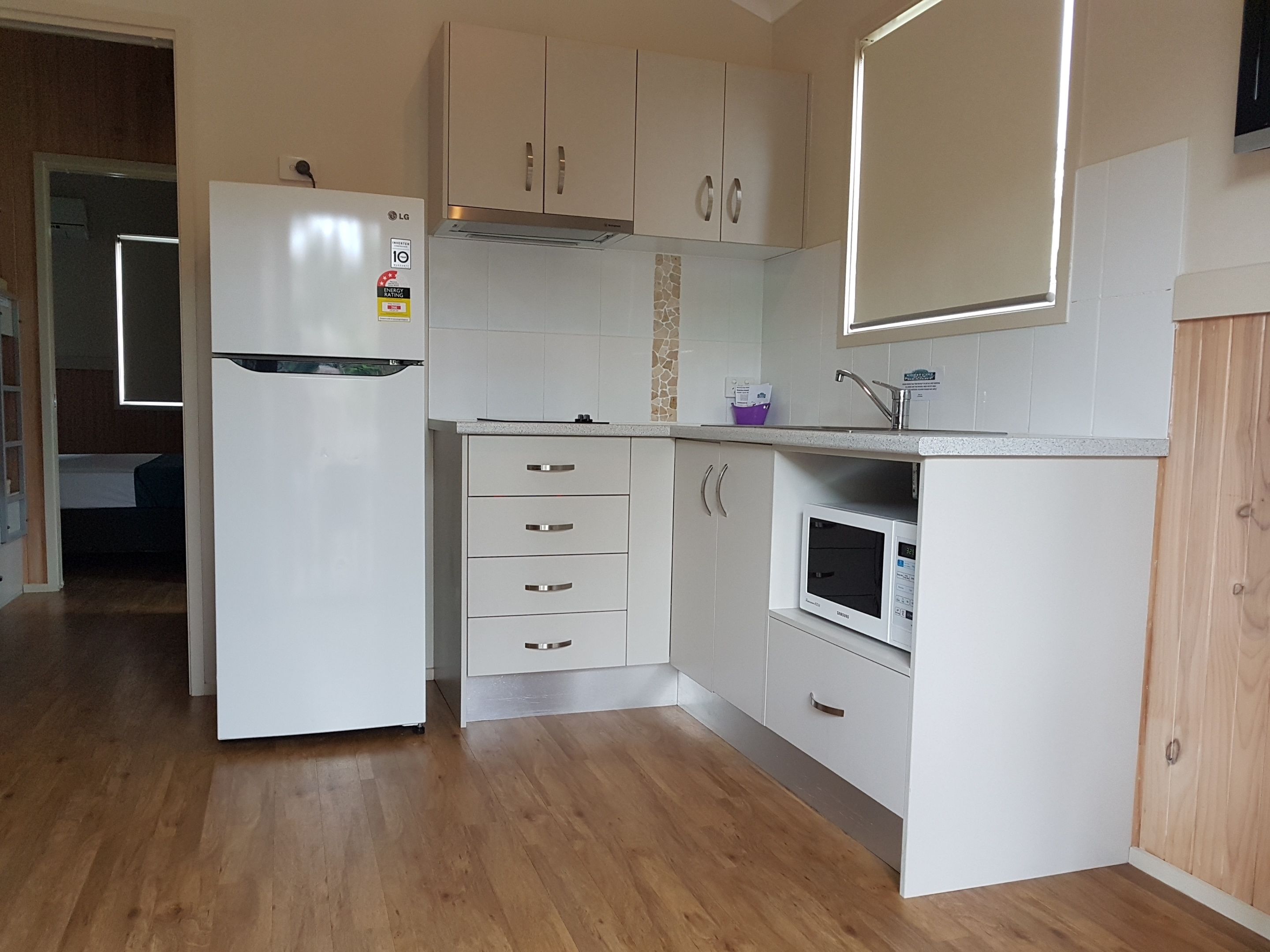 A compact kitchen with white cabinets, a built-in microwave, and a refrigerator.